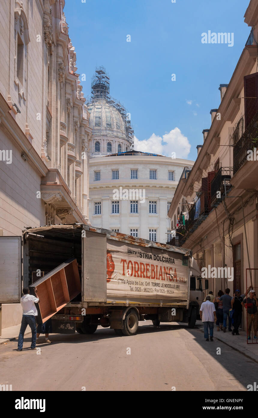 Movers rimuovere gli arredi da un carrello nella parte anteriore del Capitolio. L'Avana, Cuba. Foto Stock