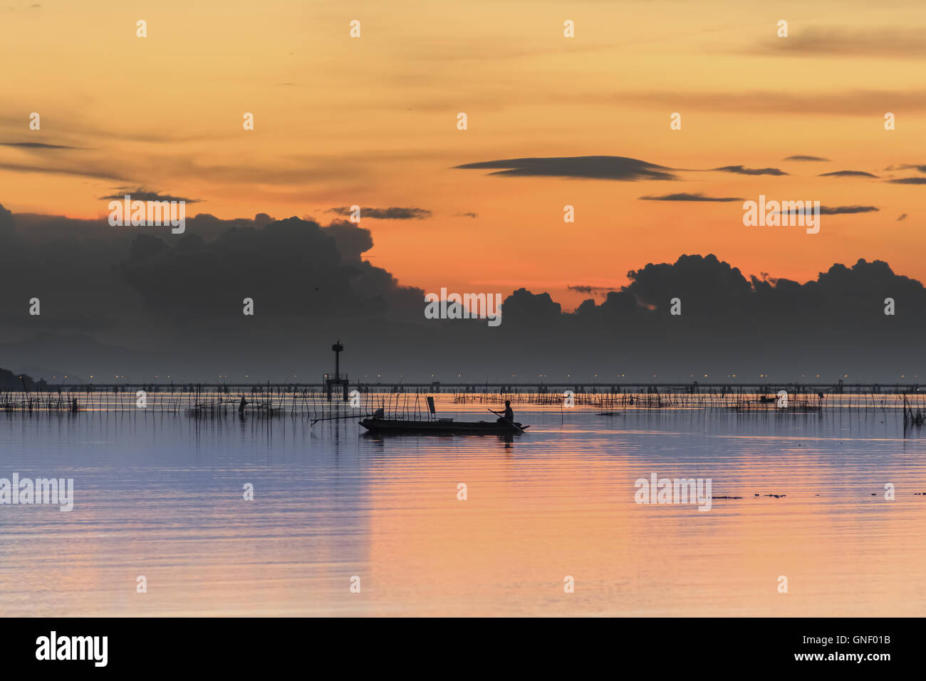 La luce del tramonto, lontano dal mare, con colorate barche da pesca ombre flottante riflettono la luce per la cattura di pesci Foto Stock