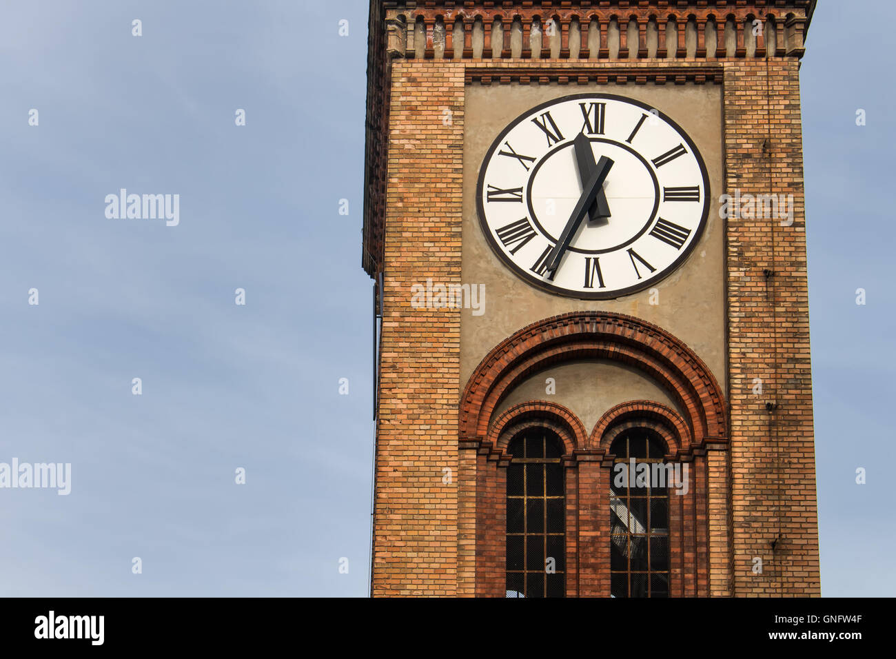 Tower con mattoni i dettagli. Orologio di contrasto con un quadrante bianco. Venti da cinque a dodici. Blue sky in background. Foto Stock