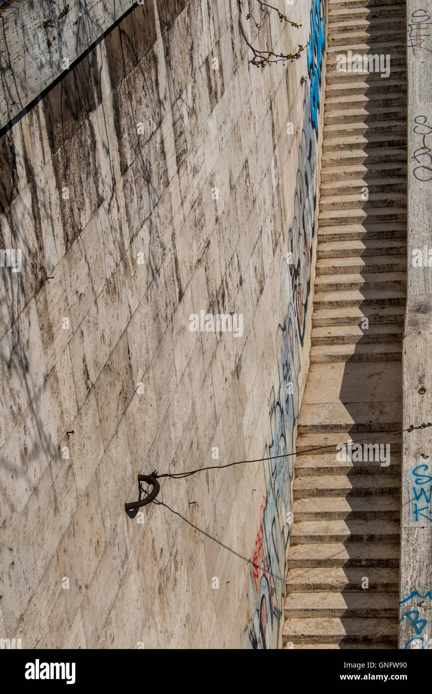 Lunga scalinata dal Tevere riverbank alla promenade. Realizzata in pietra. Parete alta sul lato sinistro con graffiti. Foto Stock