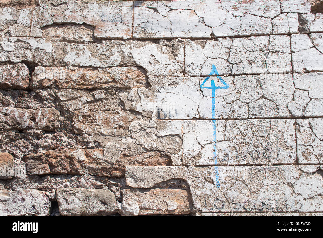 Vecchia parete danneggiata con un dipinto di blu freccia rivolta verso l'alto. Foto Stock