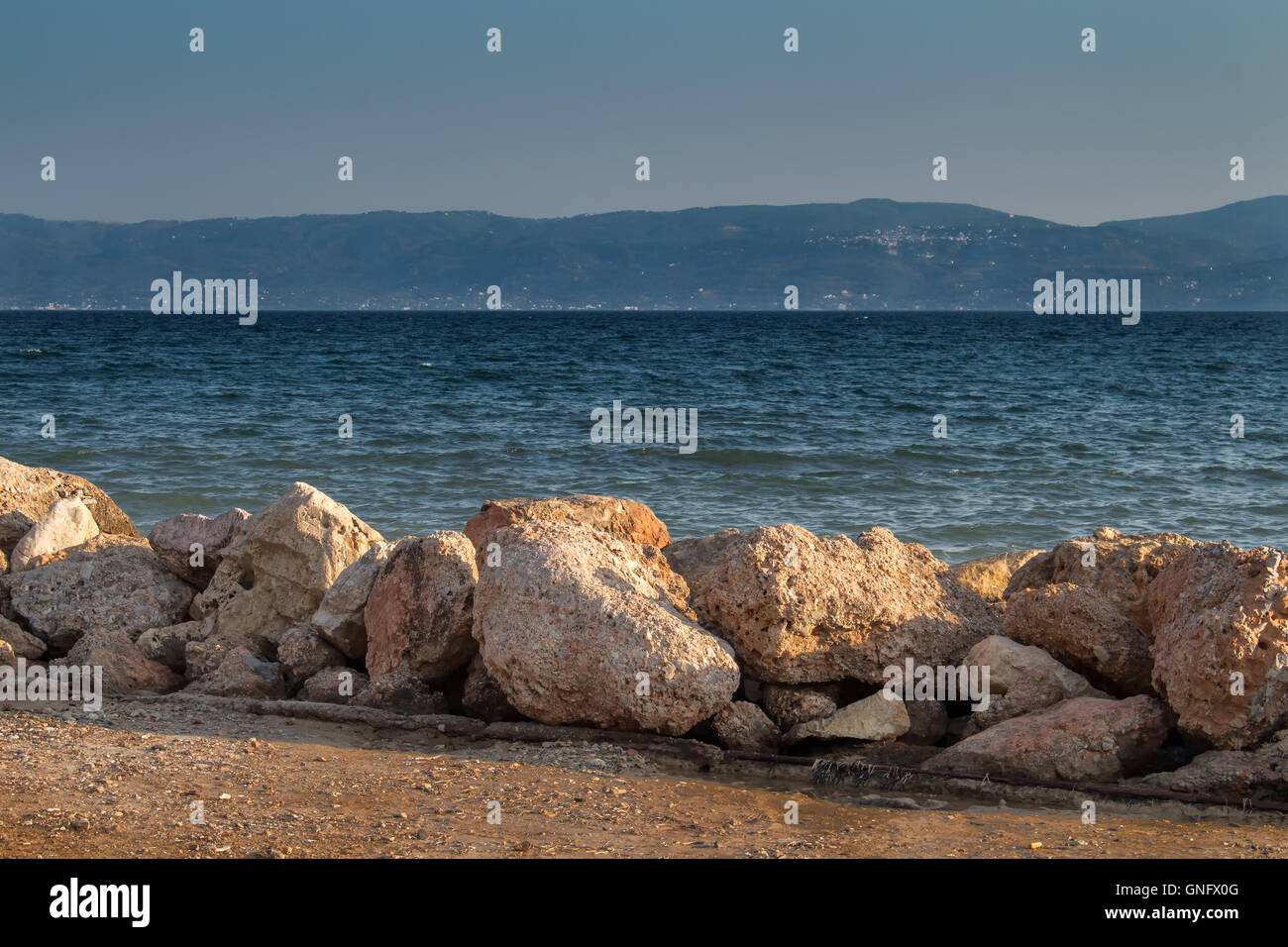 La costa della seconda più grande isola della Grecia - Eubea, posto chiamato Eretria. La linea costiera, pietre di mare con onde piccole. Foto Stock