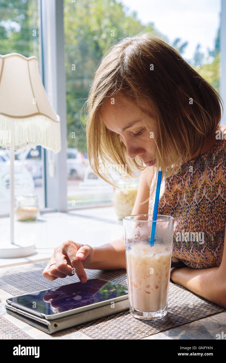 I giovani a pelo corto donna utilizzando tablet in cafe Foto Stock