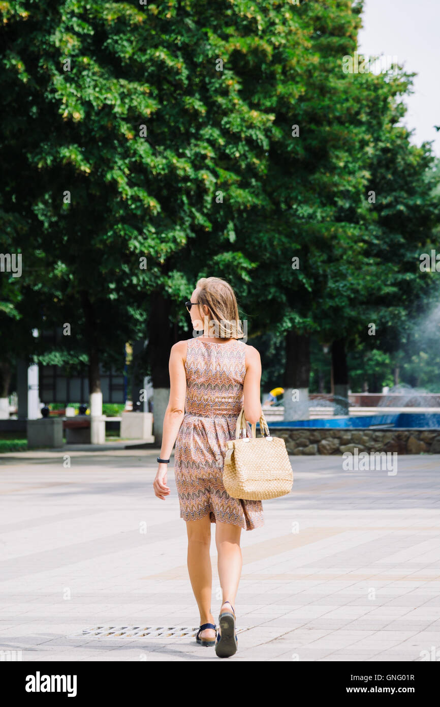 Bruna giovane donna camminare nel parco contro di fontana Foto Stock