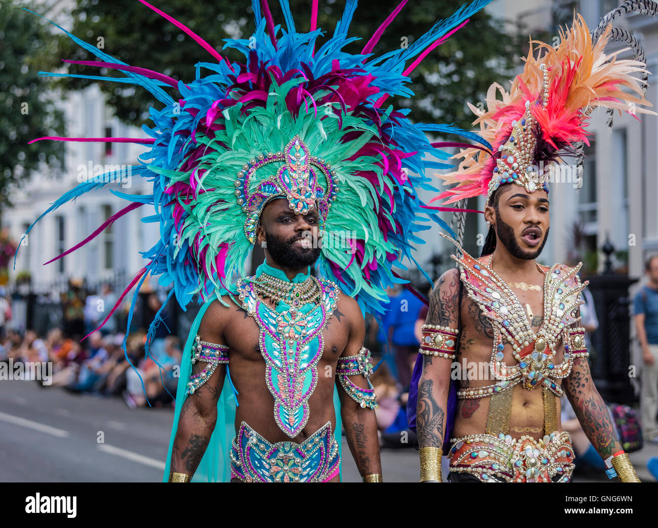 Due uomini vestiti in vivaci costumi colorati al carnevale di Notting Hill  a ovest di Londra a piedi in strada Foto stock - Alamy