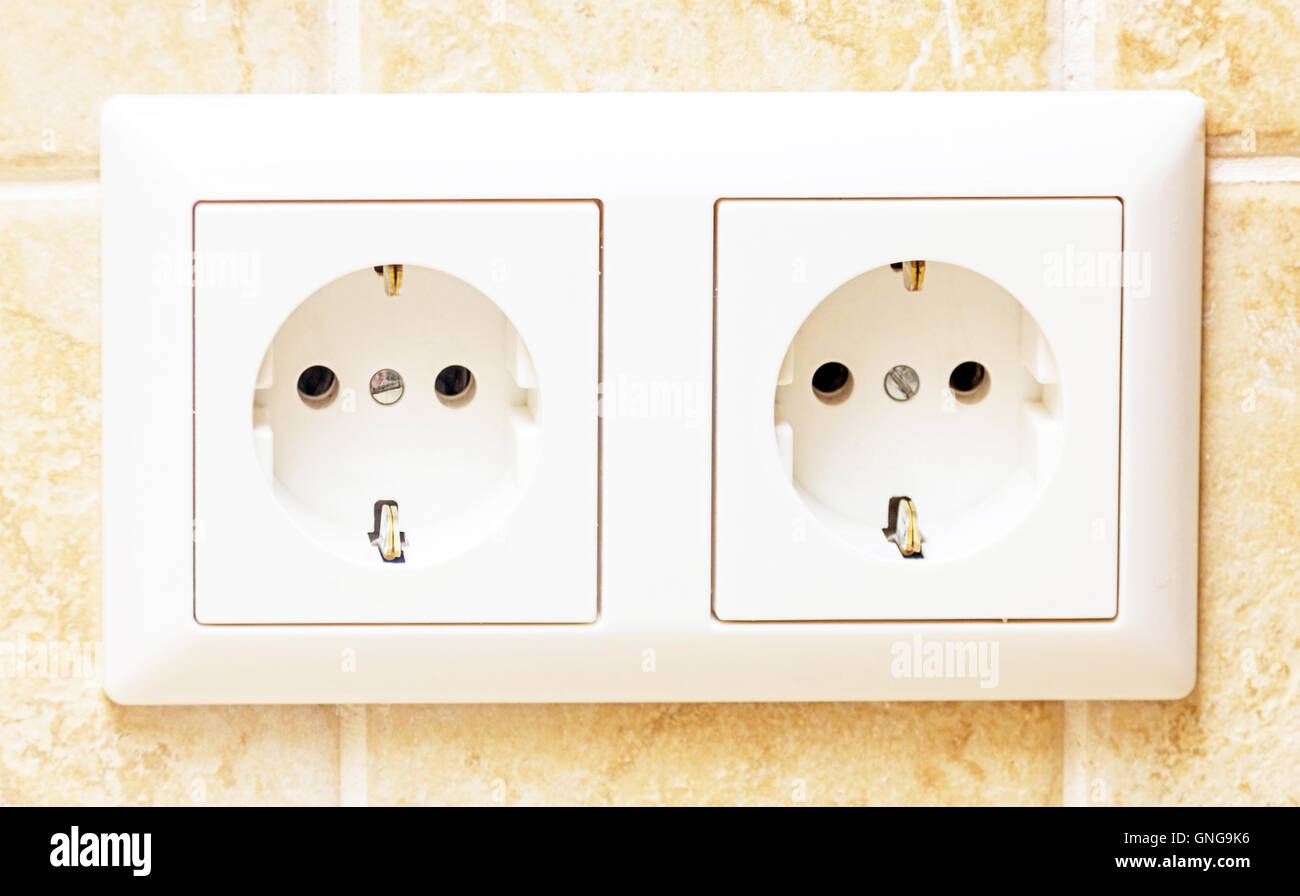 Due connettori femmina bianco luce nel muro beige Foto Stock