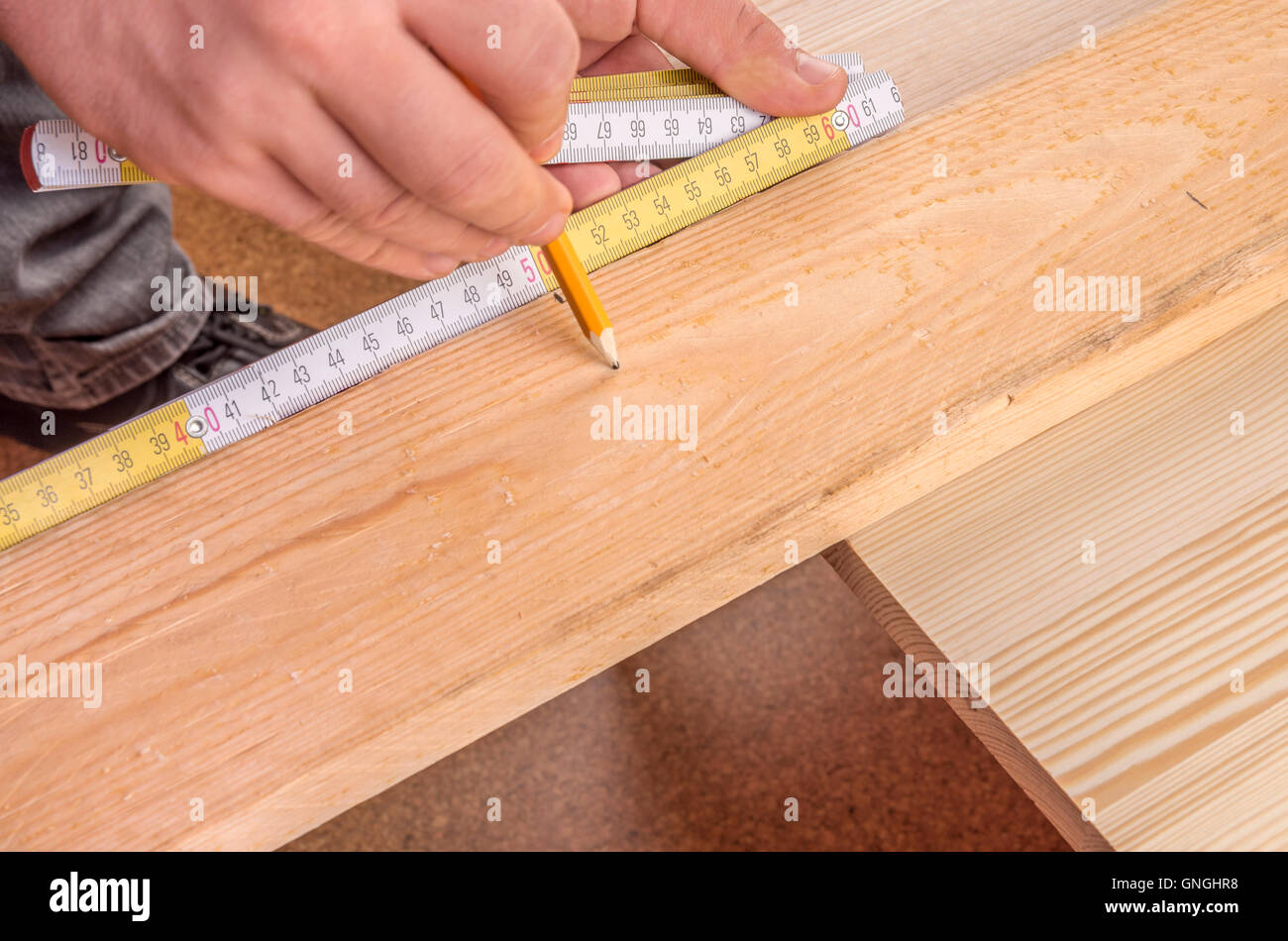 Carpenter con le mani in mano la misurazione di un pannello di legno Foto Stock