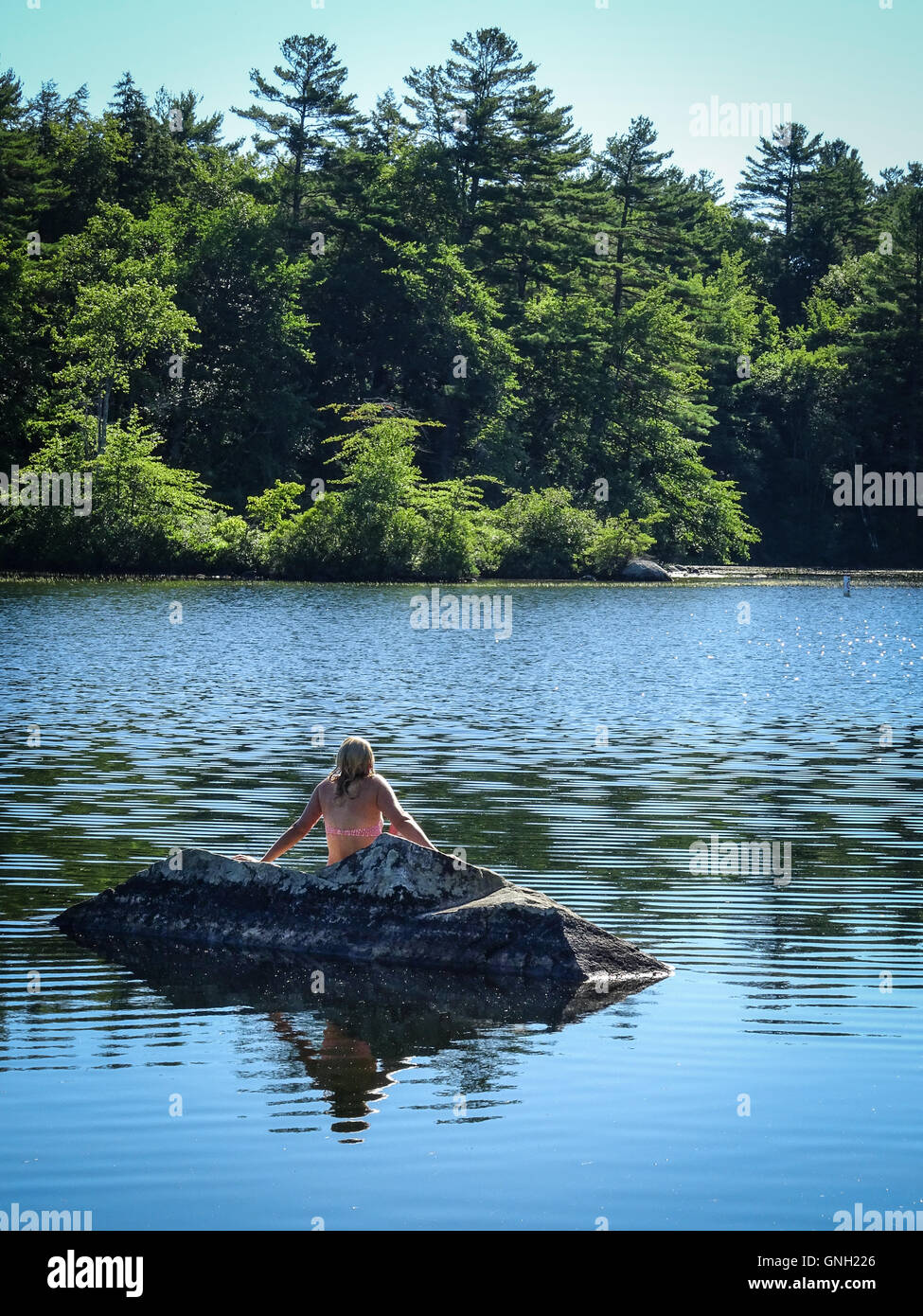 Donna seduta su una roccia, Lake Winnipesaukee, New Hampshire, Stati Uniti Foto Stock