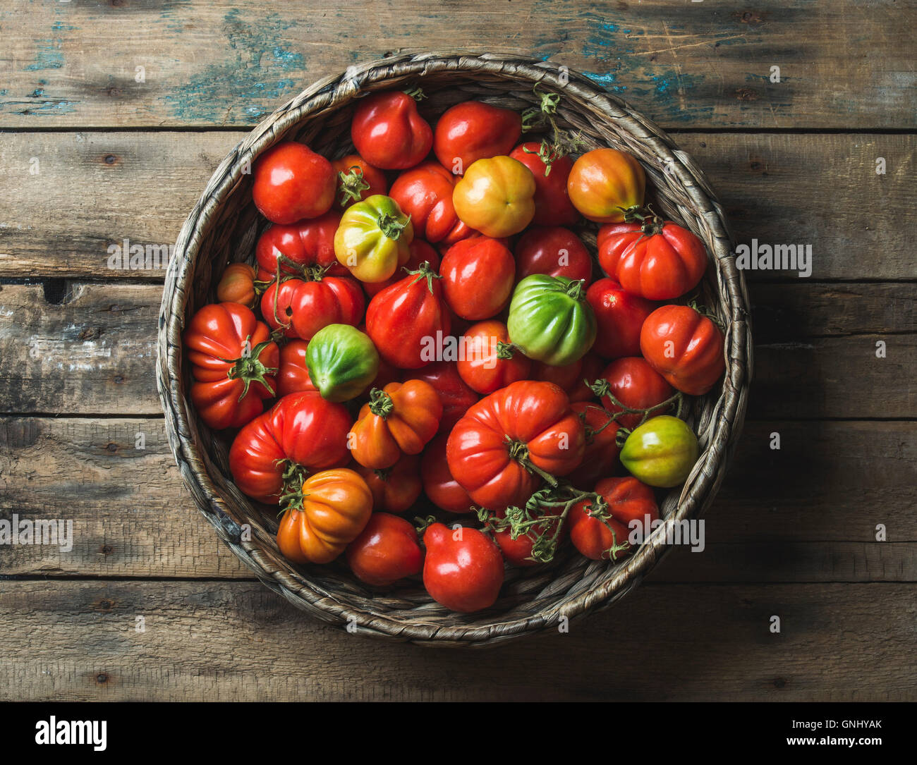 Fresh colorful ripe caduta cimelio di pomodori in cesto su sfondo di legno, vista dall'alto, composizione orizzontale Foto Stock