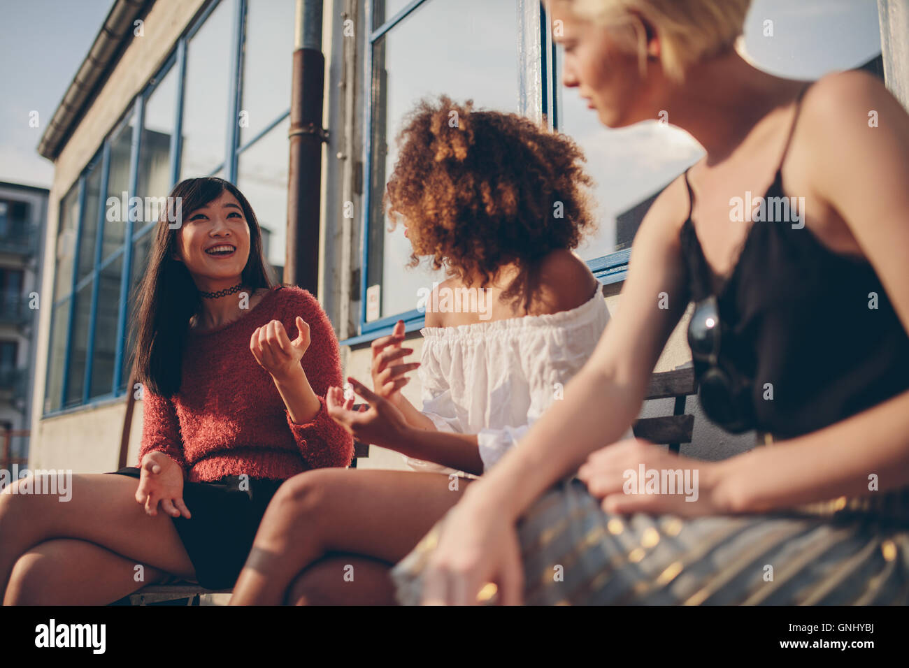 Gruppo multietnico femminile di amici seduti all'aperto e parlare. Giovani donne seduti in balcone. Foto Stock
