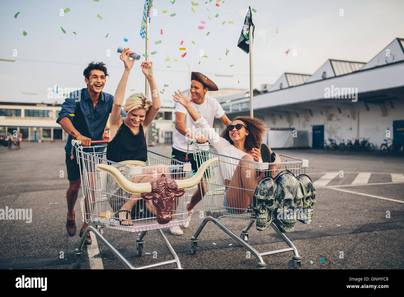 Giovani amici divertendosi su carrelli di shopping. Multietnica giovani racing sul carrello della spesa. Foto Stock