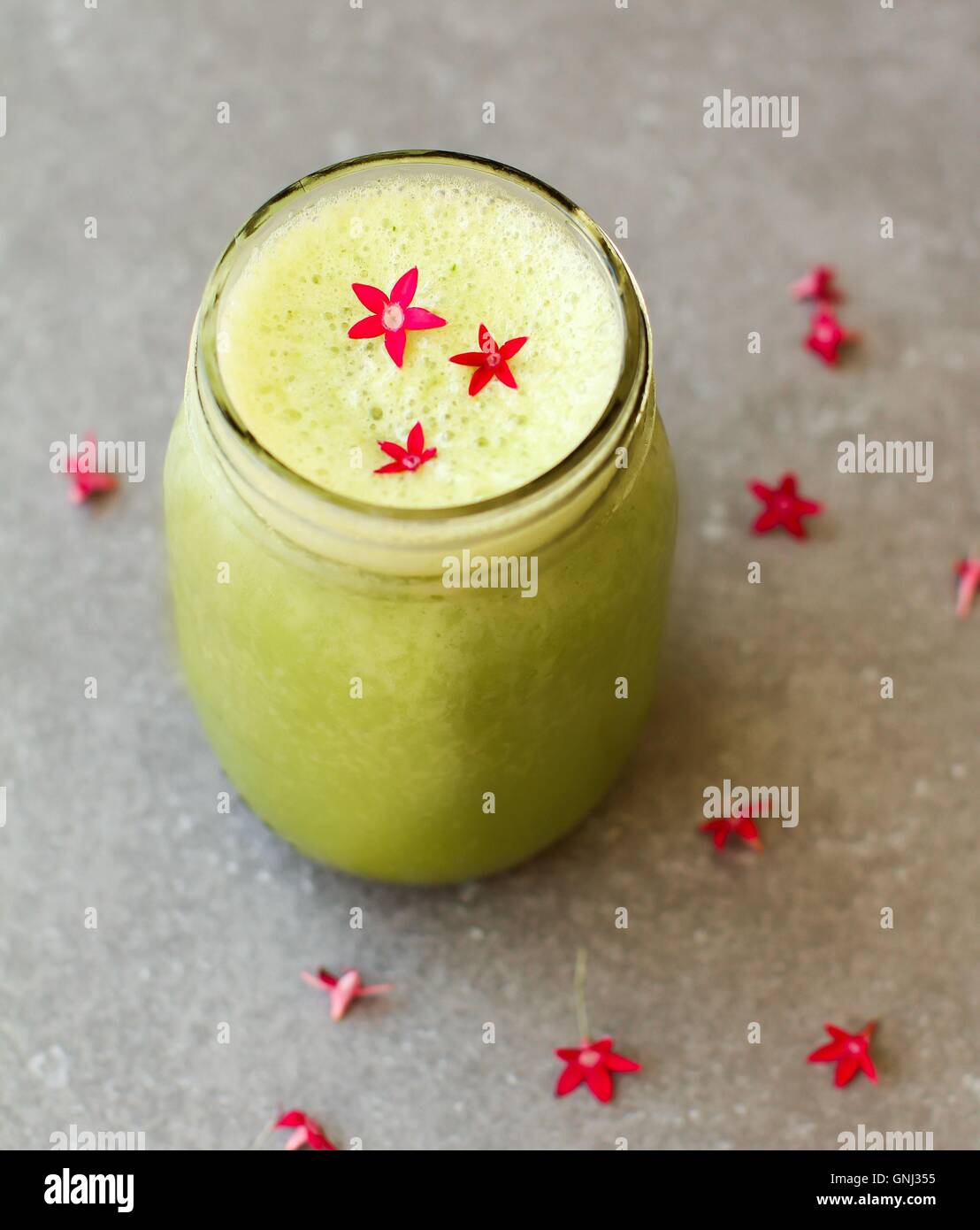Il verde di frutta e verdura bere frullato con decorazioni di fiori Foto Stock