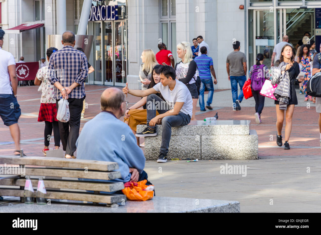 Una vista di Broad Street in Reading, Berkshire. Persone sedersi sulle panchine che server anche come una barriera per i veicoli. Foto Stock