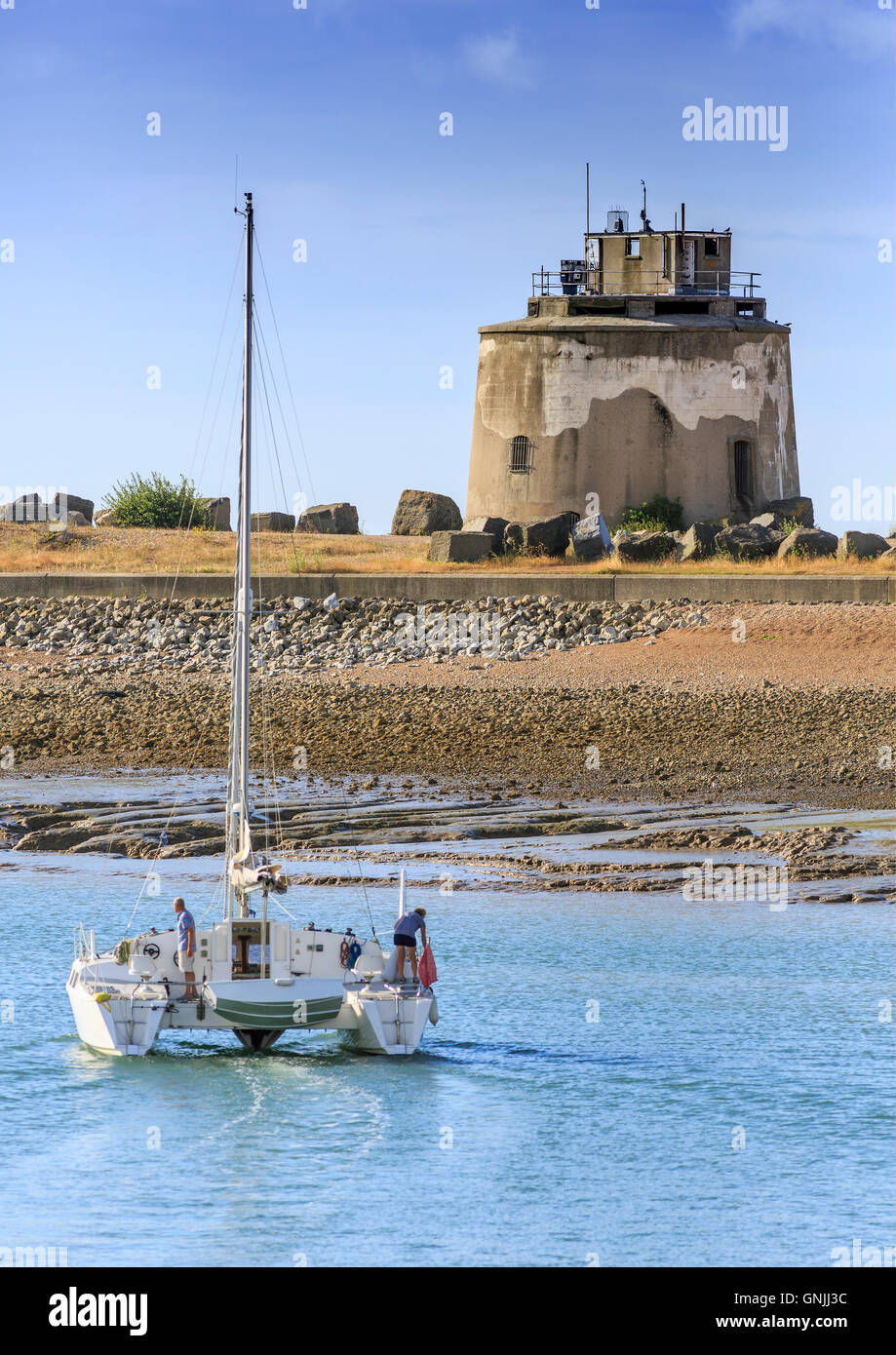 Un catamarano yacht passa un martello tower lasciando sovrano di Eastbourne Harbor estate Foto Stock