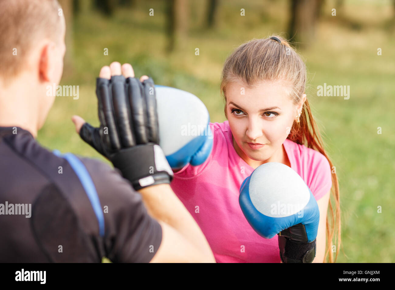 Giovane donna sportiva boxing training con istruttore presso il parco. Fitness allenamento all'aperto Foto Stock