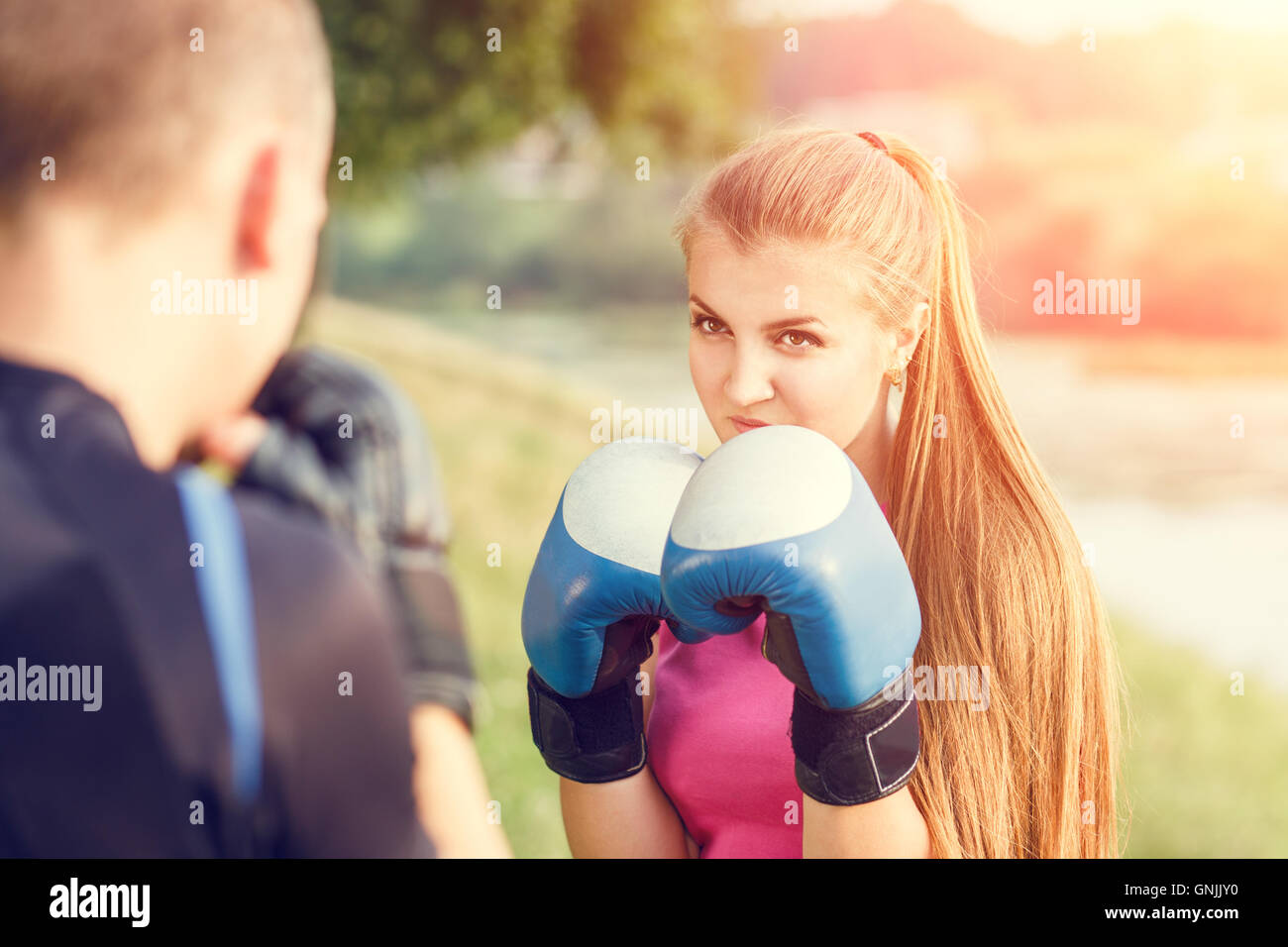 Giovane donna sportiva boxing training con istruttore presso il parco. Fitness allenamento all'aperto Foto Stock