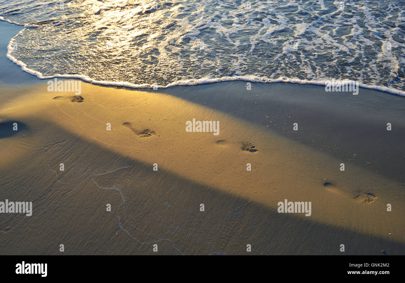 Orme nella sabbia al tramonto Foto Stock
