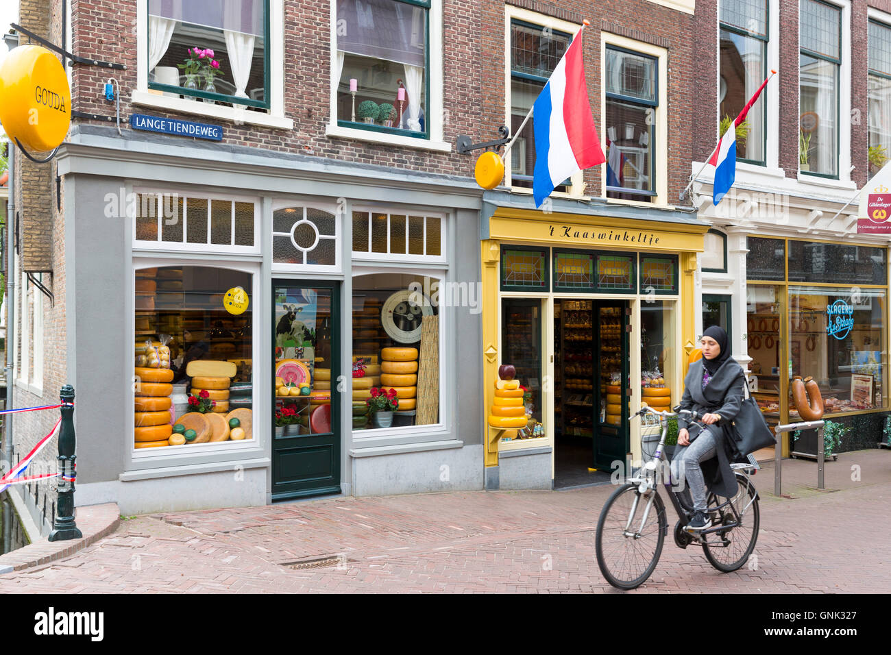 Donna che indossa velo musulmano cicli formaggio passato negozio 't Kaaswinkeltje in Lange Tiendeweg in Gouda, Holland, Paesi Bassi Foto Stock