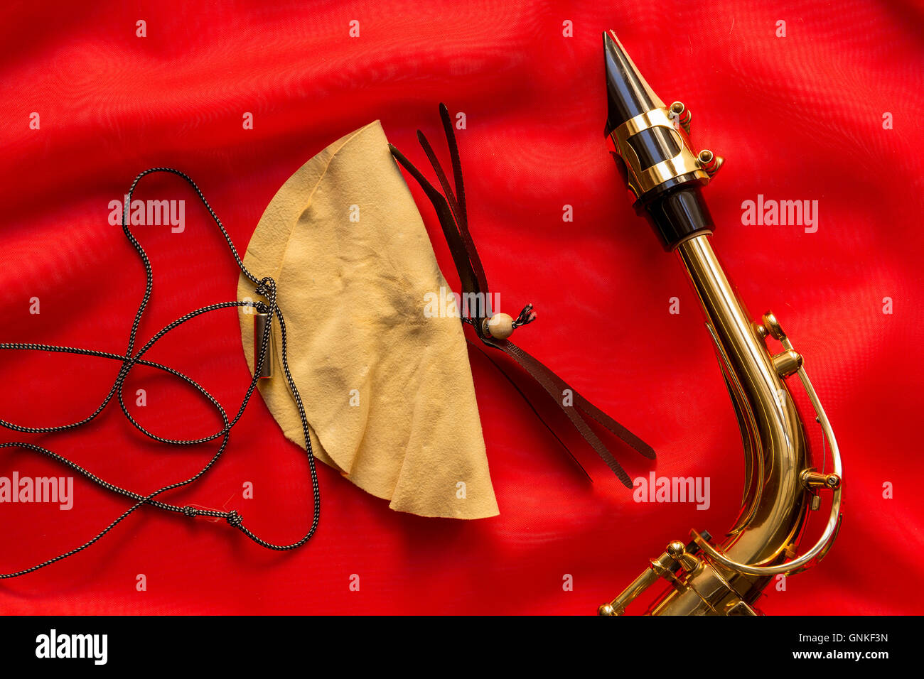 Spazzola in pelle scamosciata e sassofono boccaglio su uno sfondo rosso Foto Stock