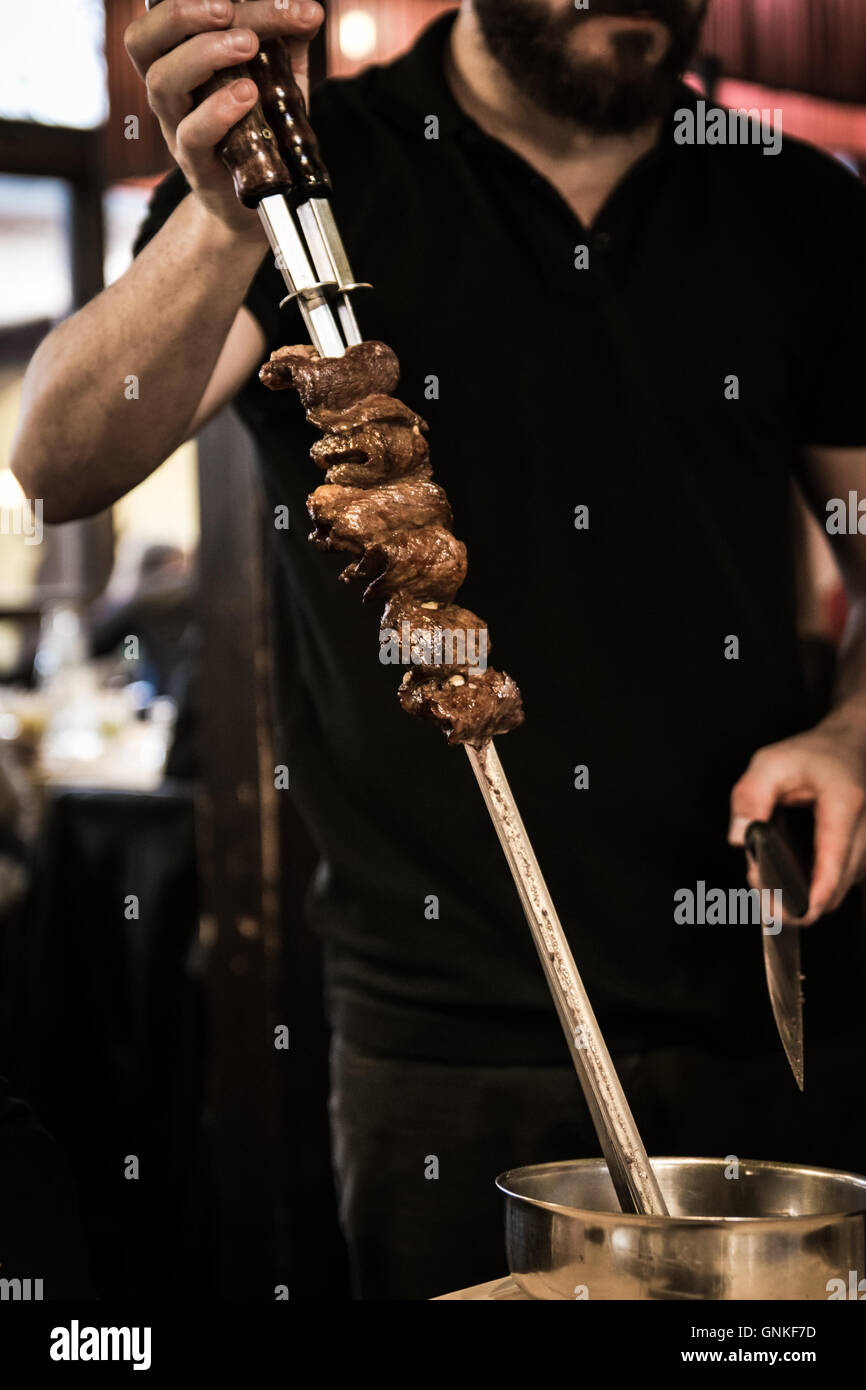 Spiedini di carne allo spiedo servita al tavolo di un ristorante brasiliano. Foto Stock