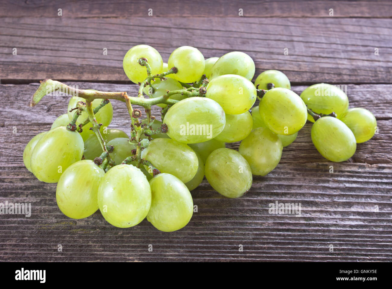 Uva bianca su sfondo di legno Foto Stock