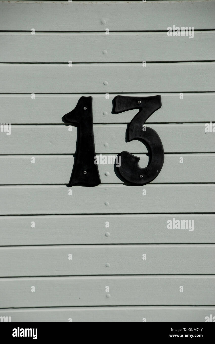 Numero 13 il numero sulla porta grigia Foto Stock