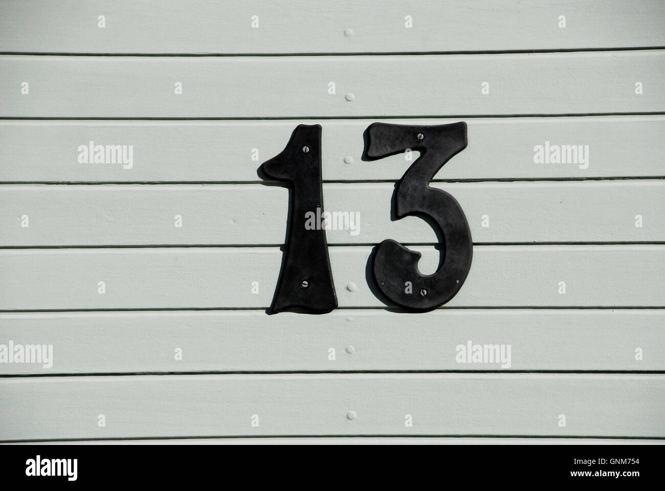 Numero 13 il numero sulla porta grigia Foto Stock