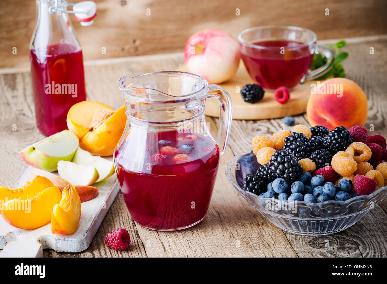 Estate Fresca di bacche e frutti in recipiente di vetro e tè di frutta con lamponi, more e mirtilli sul tavolo di legno Foto Stock