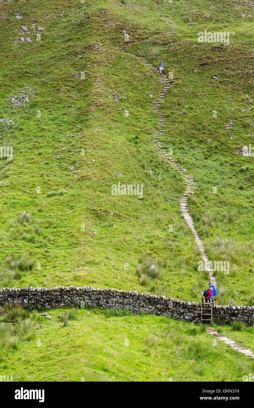 Northumberland, Inghilterra, Regno Unito. Il Vallo di Adriano (Pennine Way) sentiero ascende Walltown roccioso, due escursionisti ascendente, di un discendente Foto Stock