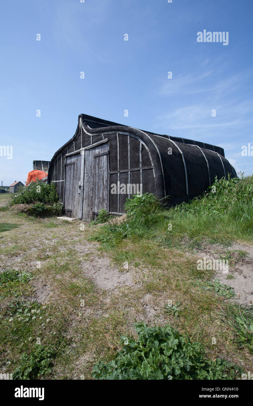 Barca capovolta utilizzato come un capannone sulla spiaggia di Lindisfarne Isola Santa Northumberland England Regno Unito Foto Stock