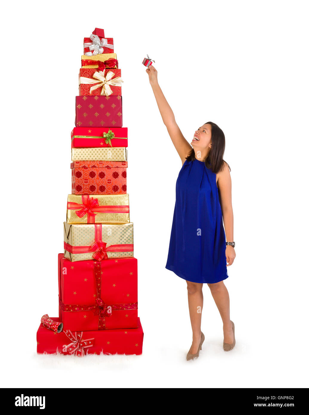 Giovane donna mettendo un piccolo dono sulla sommità di un enorme pila di regali di natale Foto Stock