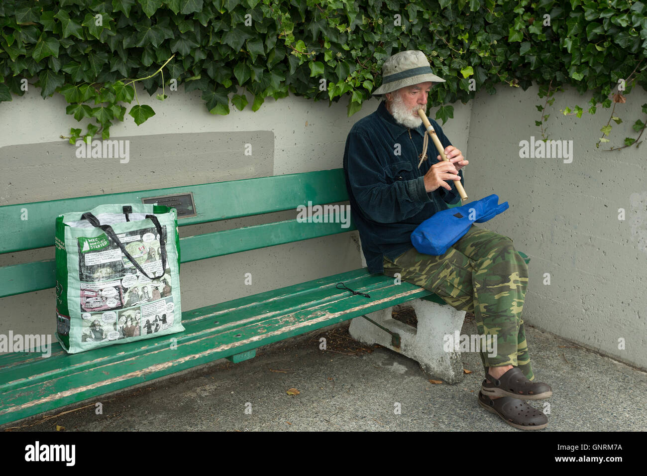 L'uomo la riproduzione di flauto sul banco in mattina presto-Victoria, British Columbia, Canada. Foto Stock