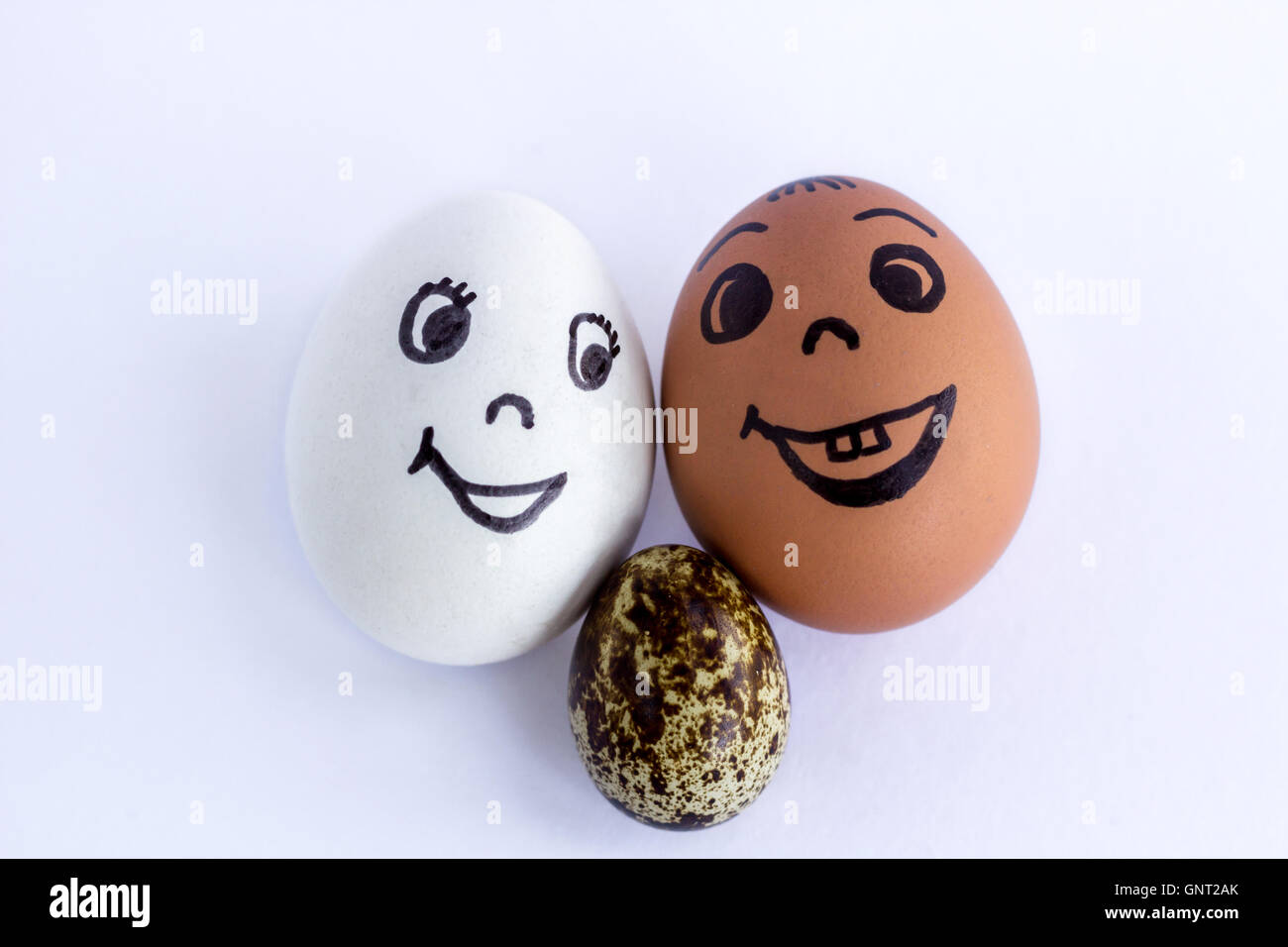 Uova divertente imitando un felice famiglia mista con versicolored bambino su sfondo bianco Foto Stock