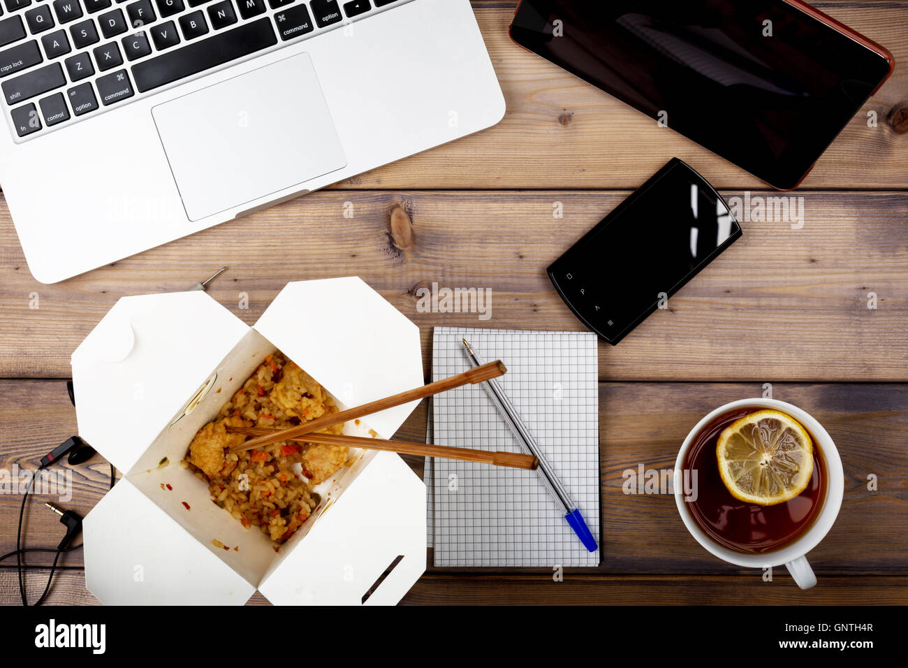 Varie di mangiare al posto di lavoro il fast food vicino sul computer portatile sul tavolo di legno Foto Stock