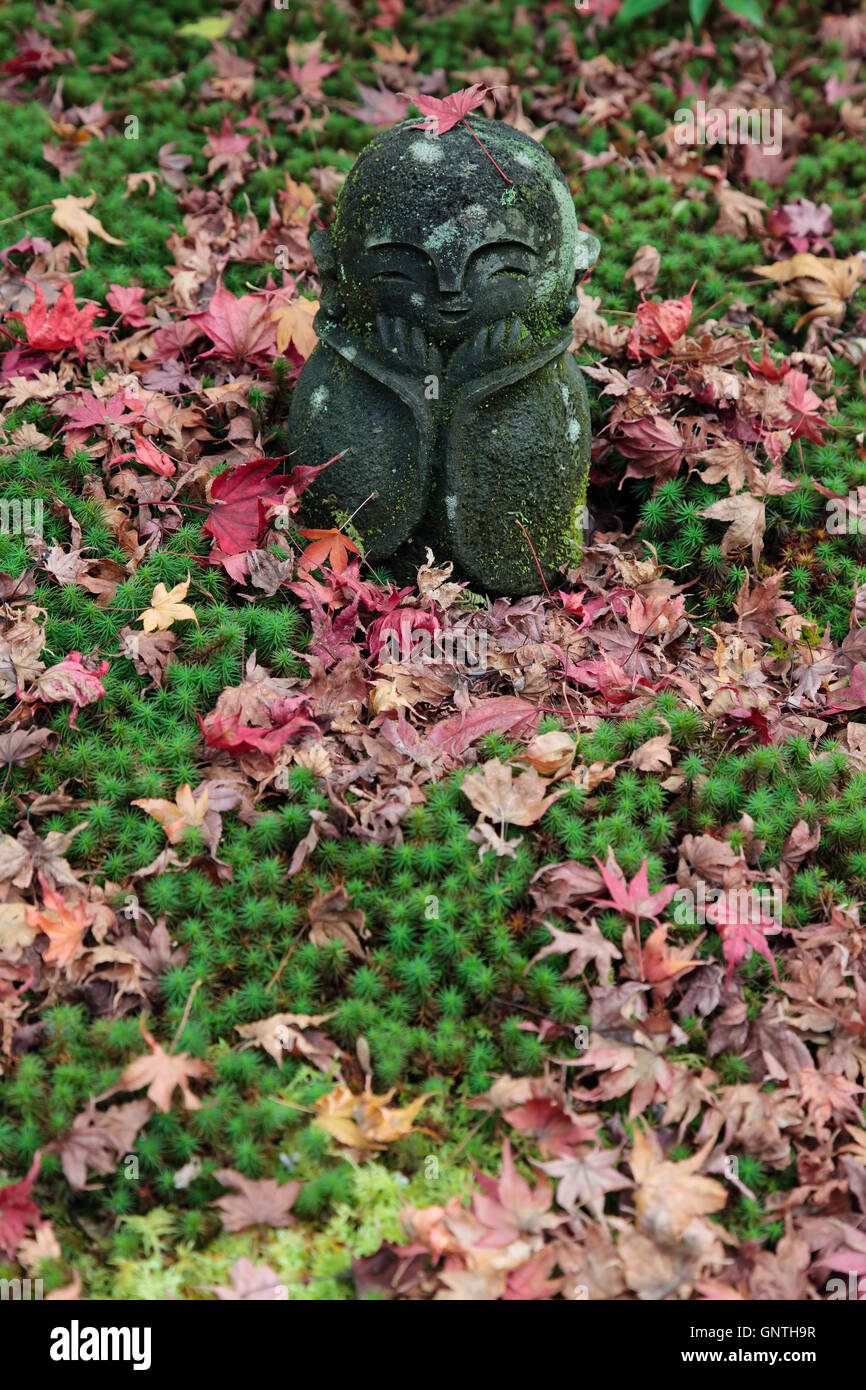 Una statua sul terreno con foglie cadute in autunno in Giappone Foto Stock