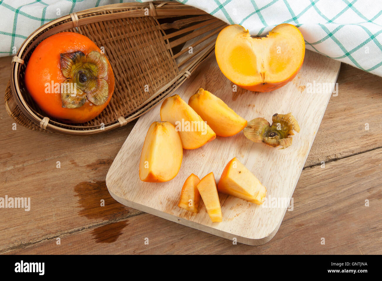 Persimmon colore giallo maturi frutti diviso sulla tavola di legno Foto Stock