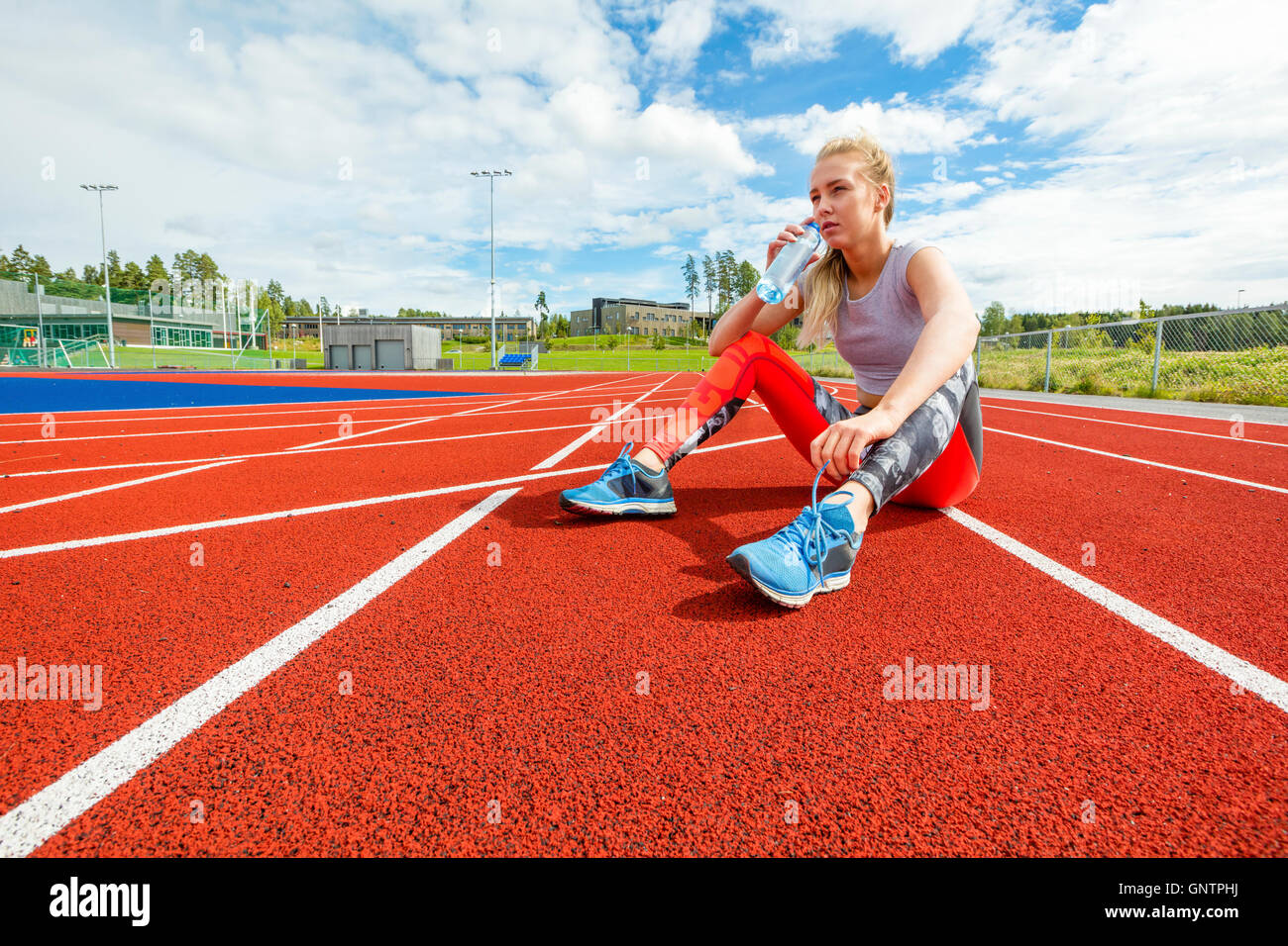 Giovane donna di acqua potabile e poggia su binari di scorrimento Foto Stock