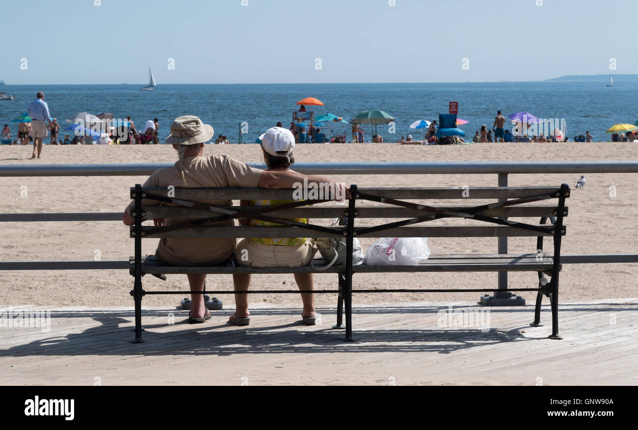 Persone di mezza età, coppia di anziani romanticamente seduta su una panchina da spiaggia affacciata sul mare sul lungomare. Foto Stock