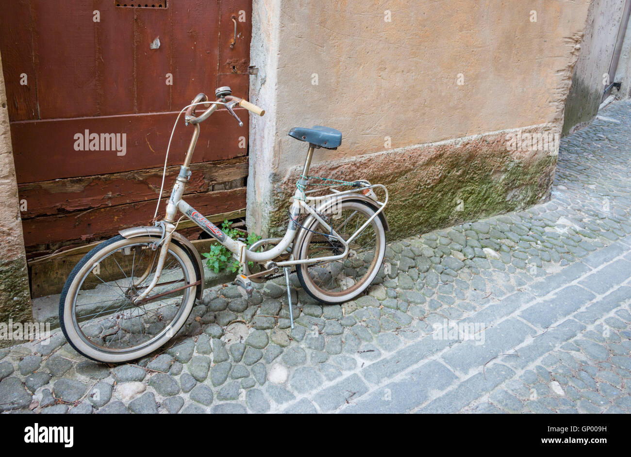 vecchio passo attraverso una bicicletta da donna in una strada acciottolata di una città francese Foto Stock
