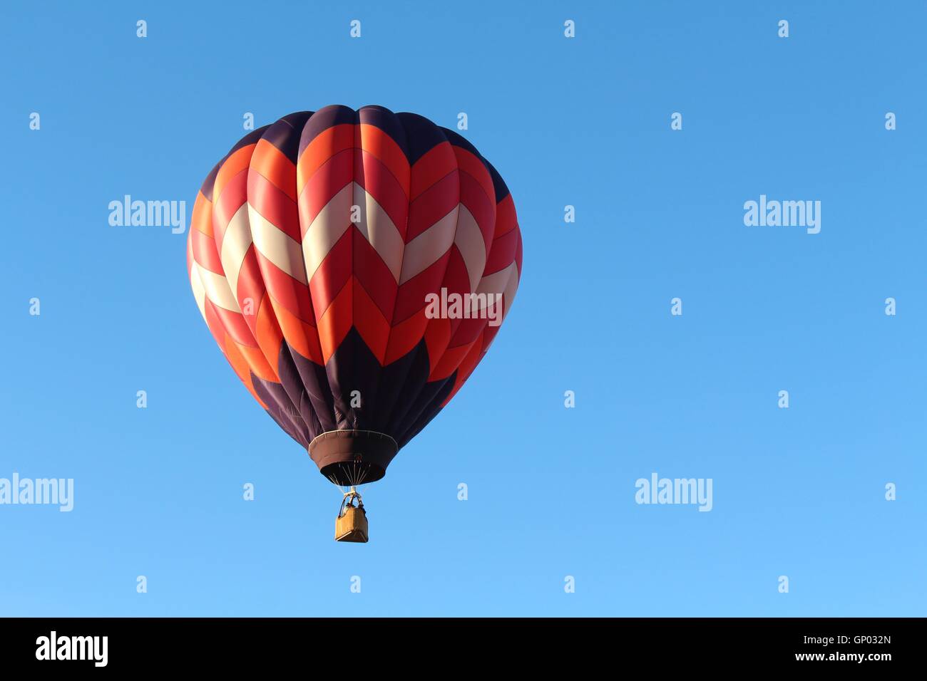 In mongolfiera ad aria calda sul luminoso cielo blu, rosso, bianco, blu Foto Stock