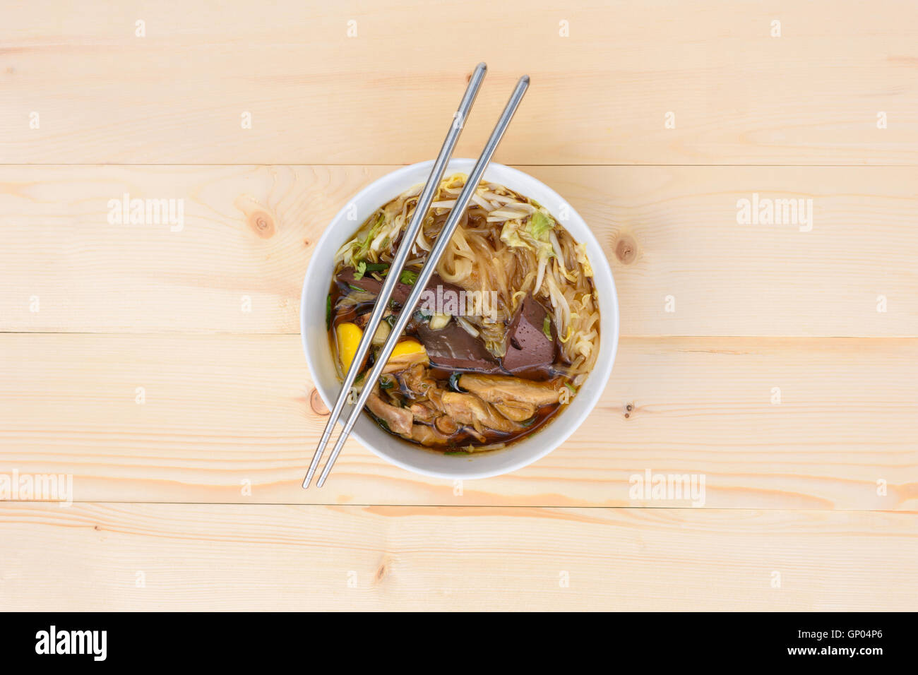 Zuppa di noodle con bacchette in ciotola su una tavola di legno, vista dall'alto, Tailandese cibo locale Foto Stock