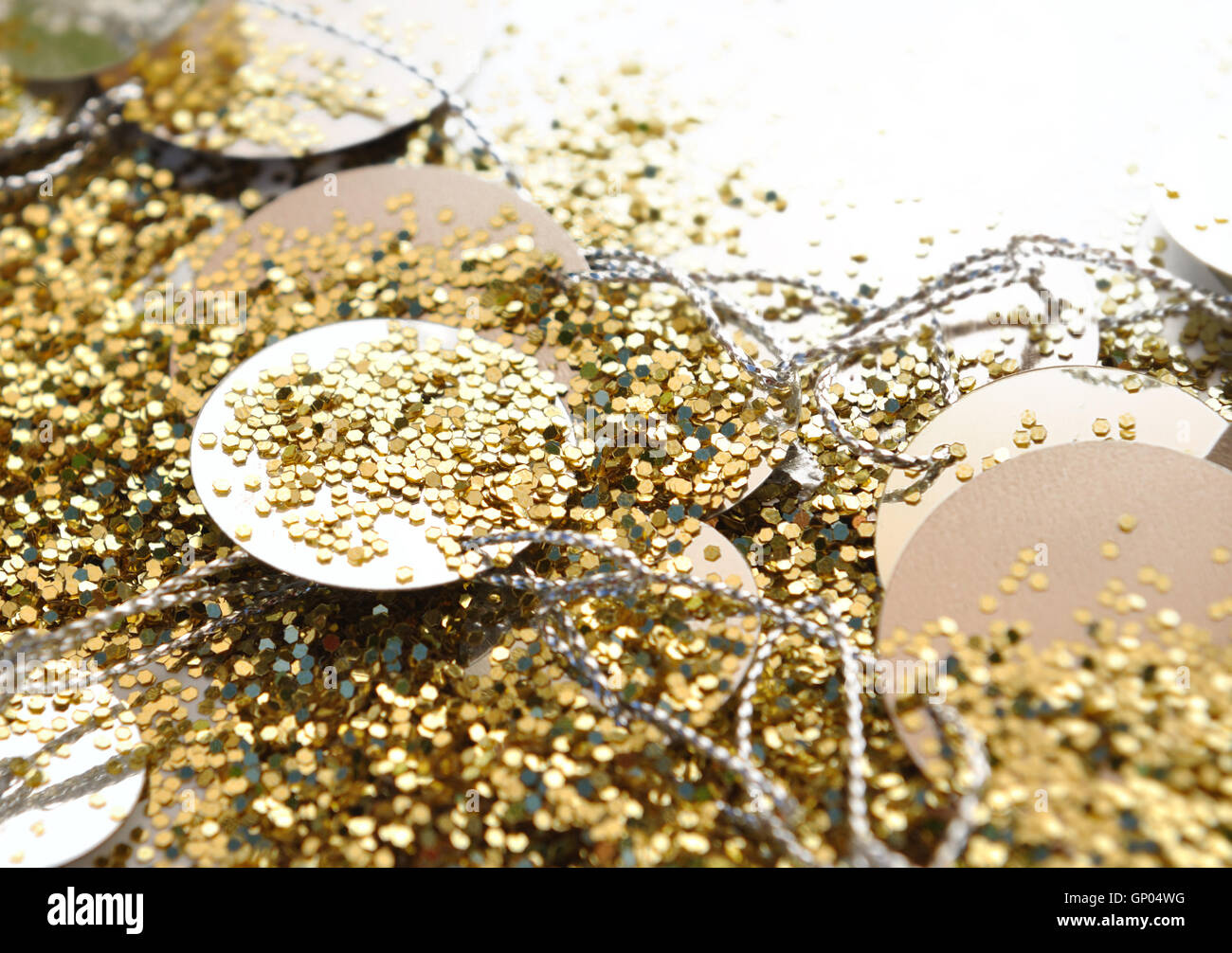 Chiudere su golden luccica e coriandoli su sfondo bianco Foto Stock