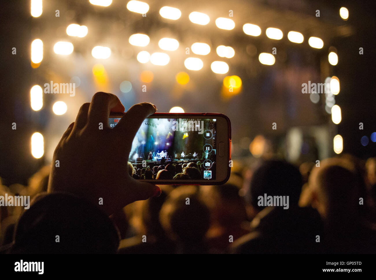 Foto di pubblico membro guardando un concerto attraverso il loro telefono cellulare. Foto Stock