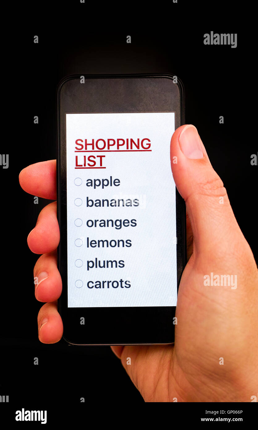 Shopping List su smart display del telefono nella donna la Mano con sfondo nero. Foto Stock