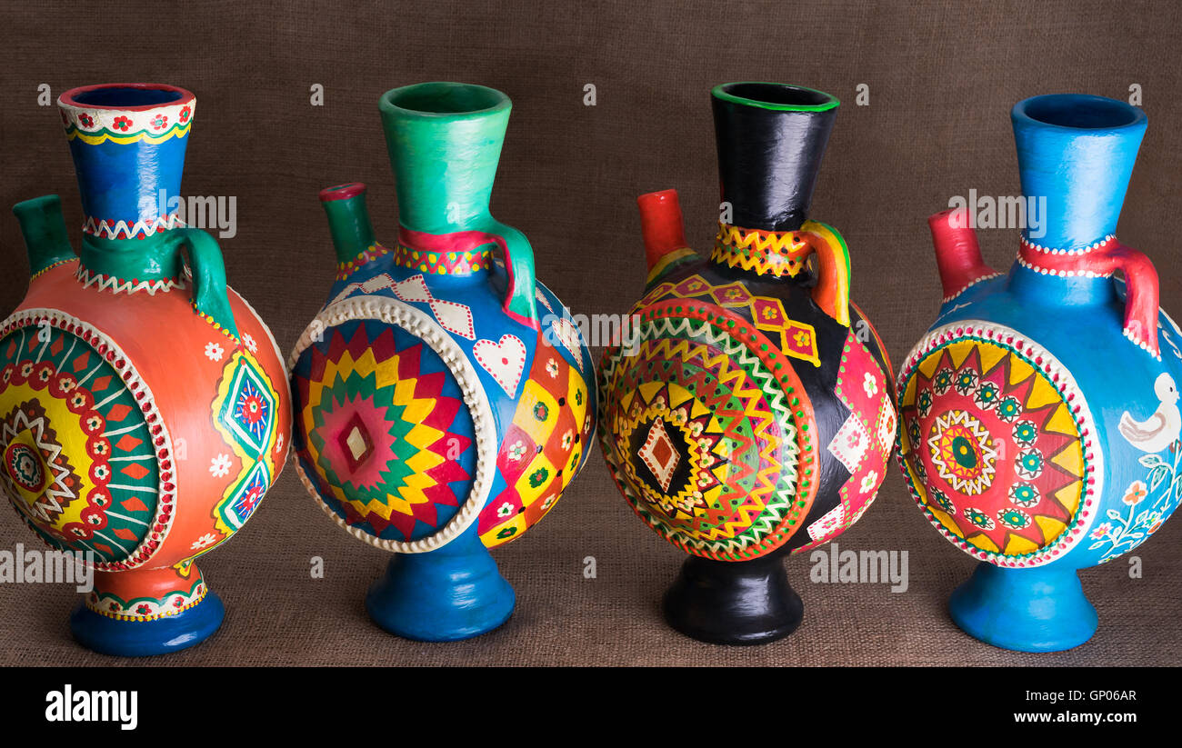 Ancora la vita di quattro decorate colorate ceramiche artigianali brocche su un letto di sacco sullo sfondo Foto Stock