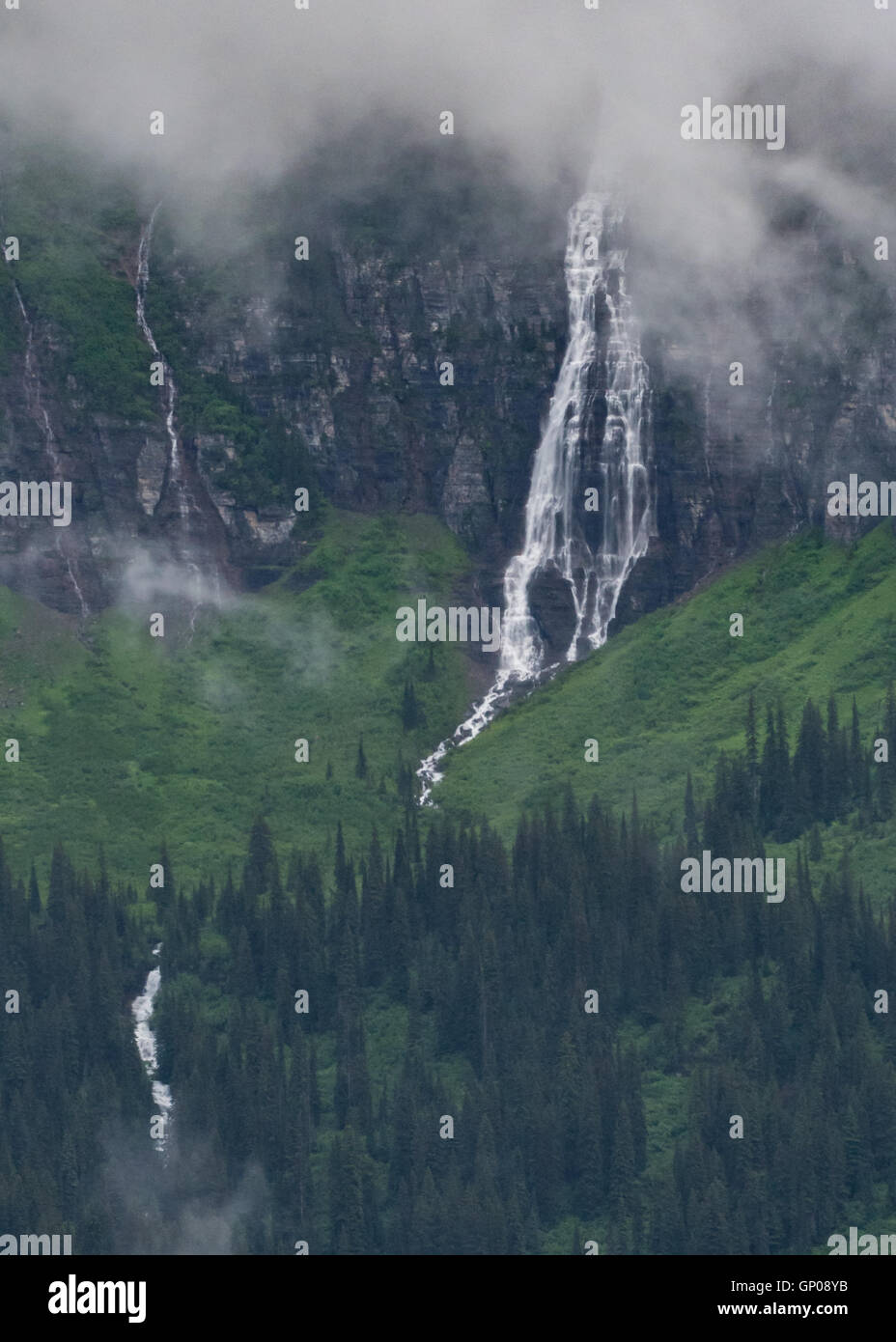 Snow Melt cascata si svuota nella lussureggiante valle verde nel Montana Monti Foto Stock