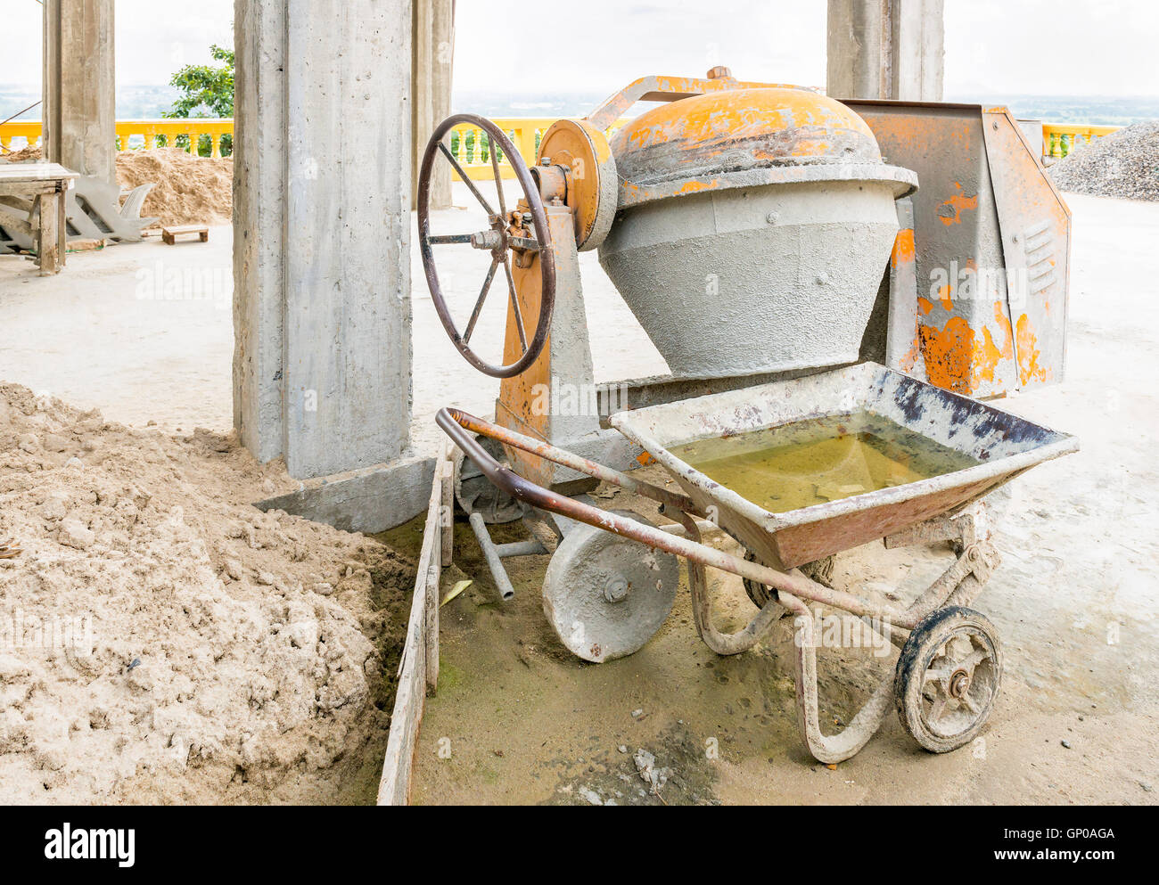 Vecchio cemento macchina miscelatrice con sabbia arresto carrello accanto a un sito in costruzione. Foto Stock