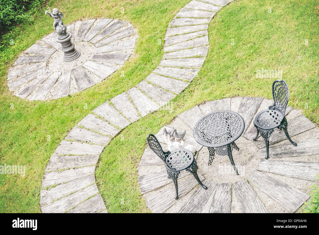 In stile vintage garden design, tabella impostata per due mobili, stucco, marciapiede e l'erba verde. Foto Stock