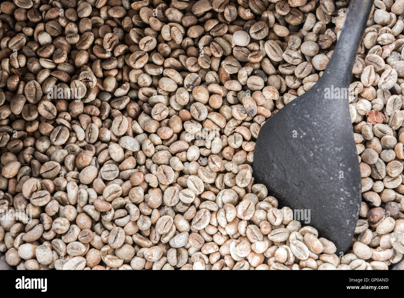 Chicchi verdi di caffè con una vecchia ciotola di legno, pronti per essere arrostiti. Foto Stock