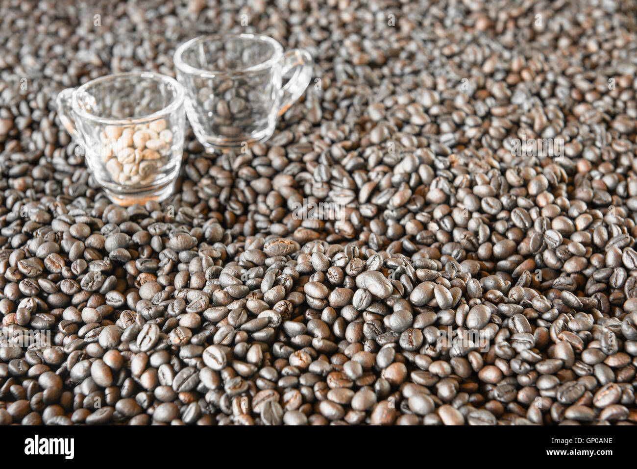 Chicchi di caffè tostati con sfocata 2 tazzine di caffè sul fondo. Foto Stock